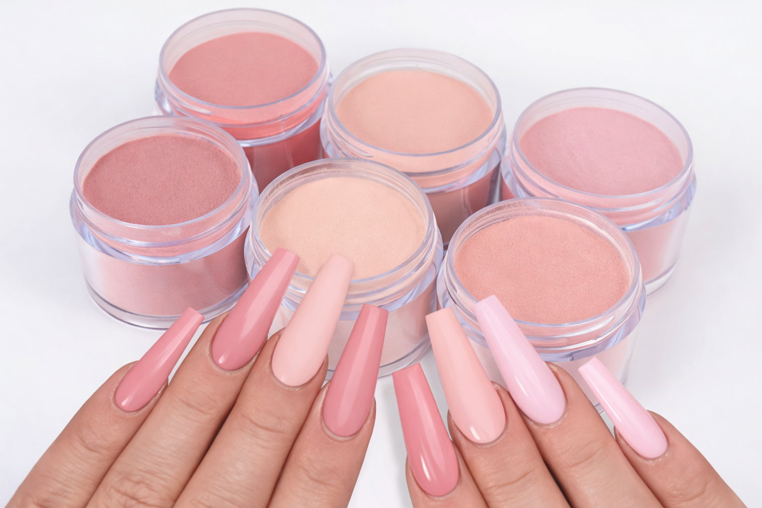 Long coffin-shaped acrylic nails in soft pink shades displayed with matching dip powder jars on a white background.